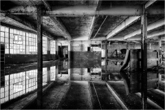 Abandoned interior space with reflective surfaces and industrial architecture.