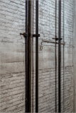 Industrial vertical pipes against textured concrete wall, showcasing urban decay and architecture.
