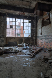 Abandoned space with broken windows and debris scattered on the floor.