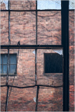 Old brick walls framed by broken windows, capturing urban decay.