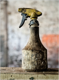 Worn sprayer rests still, dust and time have intertwined.