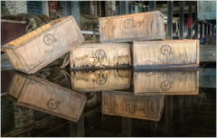 Wooden crates stacked high, reflections dance on the floor.