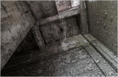 Weathered walls whisper stories of a forgotten past, drenched in shadows and decay.