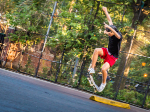 A young acrobat defies gravity mid-air while skateboarding, quite pleased with themselves.