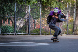 A skater in mid-air doing tricks with an enthusiastic purple outfit.