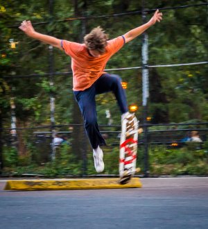 A skateboarder defies gravity mid-air, wildly leaping over a yellow curb.