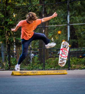 A daring skateboarder attempts a gravity-defying trick over an unsuspecting yellow ramp.