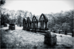 A row of weathered gravestones under a haunting sky.