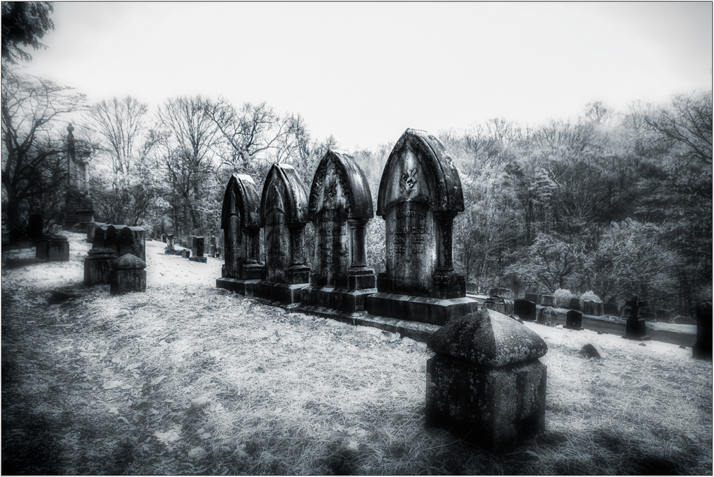 A row of weathered gravestones under a haunting sky.