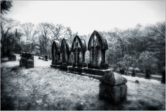 A row of weathered gravestones under a haunting sky.
