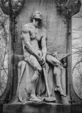 A ghastly yet delightful stone figure, muscular and contemplative, clutching tools of labor.