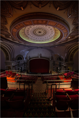 An ornate theater interior with a grand ceiling and red seating.