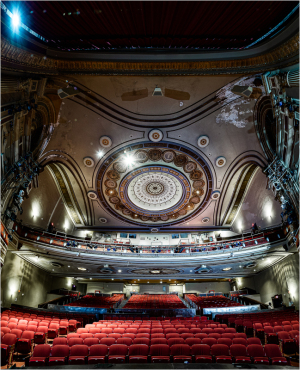 Interior view of a grand theater with ornate ceiling and red seats.