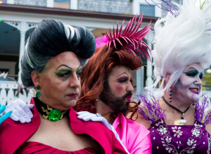 Three individuals in vibrant costumes and makeup, showcasing creativity and expression.