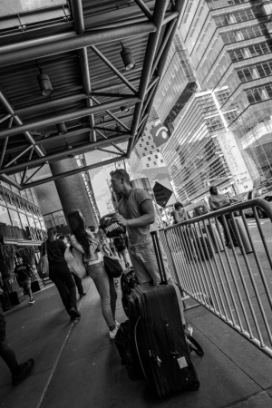 A bustling urban scene with people and luggage against a backdrop of tall buildings.