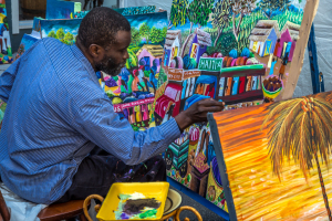 Artist brings vibrant colors to life with a brush, surrounded by lively canvases.