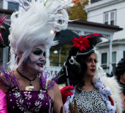 Two fabulous individuals dressed in extravagant outfits with dramatic hairstyles and makeup.