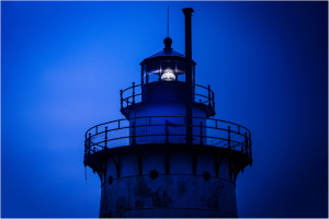 Tarrytown Lighthouse illuminated at dusk, showcasing its structure and light mechanism.