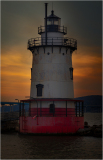 Tarrytown Lighthouse stands against a sunset, reflecting on the water's surface.