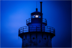 Tarrytown Lighthouse illuminated at dusk, showcasing its structure and light mechanism.