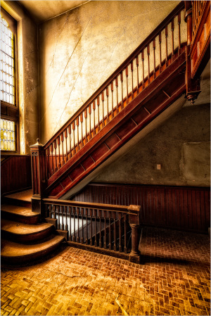 Staircase in a faded building, wood and stone in disrepair, echoes of former life linger