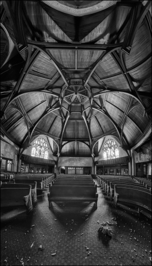 A hauntingly beautiful interior of a decayed church, wood beams loom ominously.