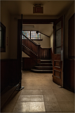 A dimly lit exit leading to a staircase, hinting at hidden corridors and forgotten stories.