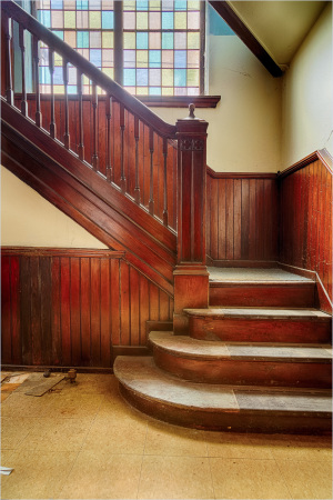 Intricate wooden staircase with colorful stained glass above; a hidden gem of the past.