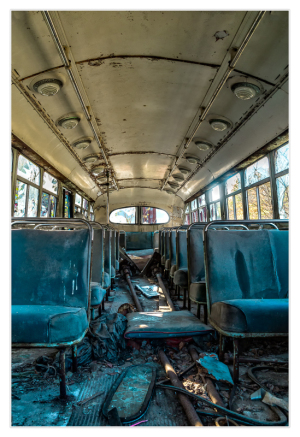 Interior of an abandoned trolley bus with worn seats and debris on the floor.