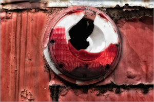 Red and white circular object with a large hole, showing wear on a rusty surface.