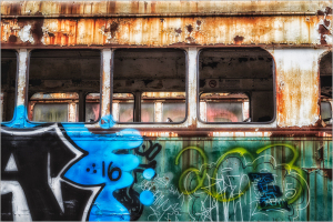Weathered trolley with vibrant graffiti and rusty textures, showcasing urban decay.