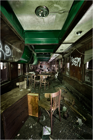 An abandoned, decaying interior of a trolley, filled with dust and shadows.