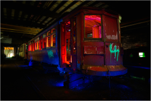 A rusted trolley car sits in a dimly lit space, remnants of a bygone era.