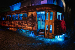 Abandoned trolley car illuminated in blue light, showcasing urban decay and forgotten transit history.
