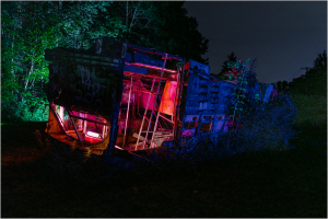 Abandoned trolley in a graveyard, illuminated by colorful lights.
