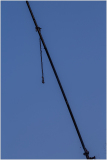 A solitary crane arm silhouetted against a clear blue sky.