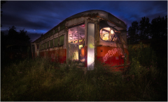 An abandoned trolley car, rusting in the shadows, overgrown with weeds under a twilight sky.