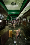 An abandoned, decaying interior of a trolley, filled with dust and shadows.