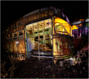 An abandoned trolley, rusted and peeling, looms in the shadows of a graveyard.