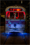 An old trolley with vibrant red and blue lights, resting in a dimly lit space.