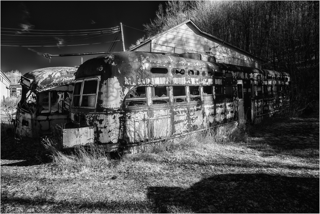 An abandoned, rusted trolley lies amidst overgrown weeds, a relic of forgotten journeys.