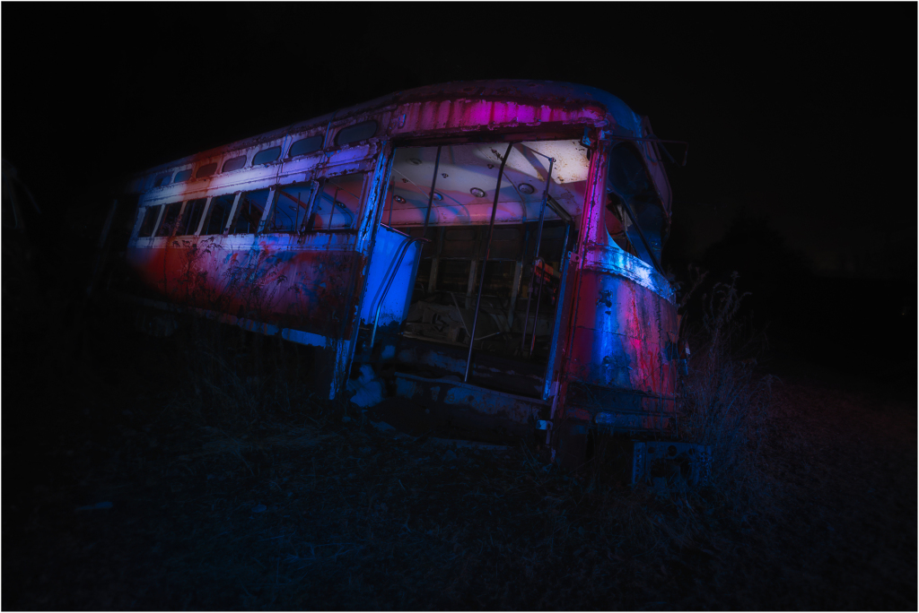 An abandoned trolley, rusted and forlorn, looms in the darkness, shrouded in eldritch hues.