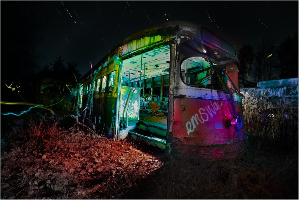 An abandoned trolley, cloaked in shadows, emanates an eldritch glow amidst the encroaching darkness.
