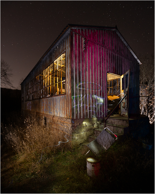 A forsaken structure, its weathered facade illuminated by an otherworldly glow, looms in the night.