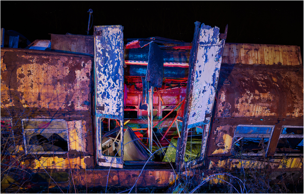 A rusted trolley car stands in eerie silence, its peeling paint revealing shadows of forgotten stories.