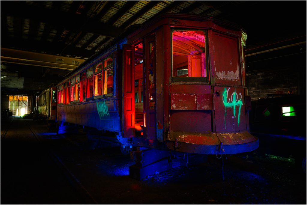 A rusted trolley car sits in a dimly lit space, remnants of a bygone era.