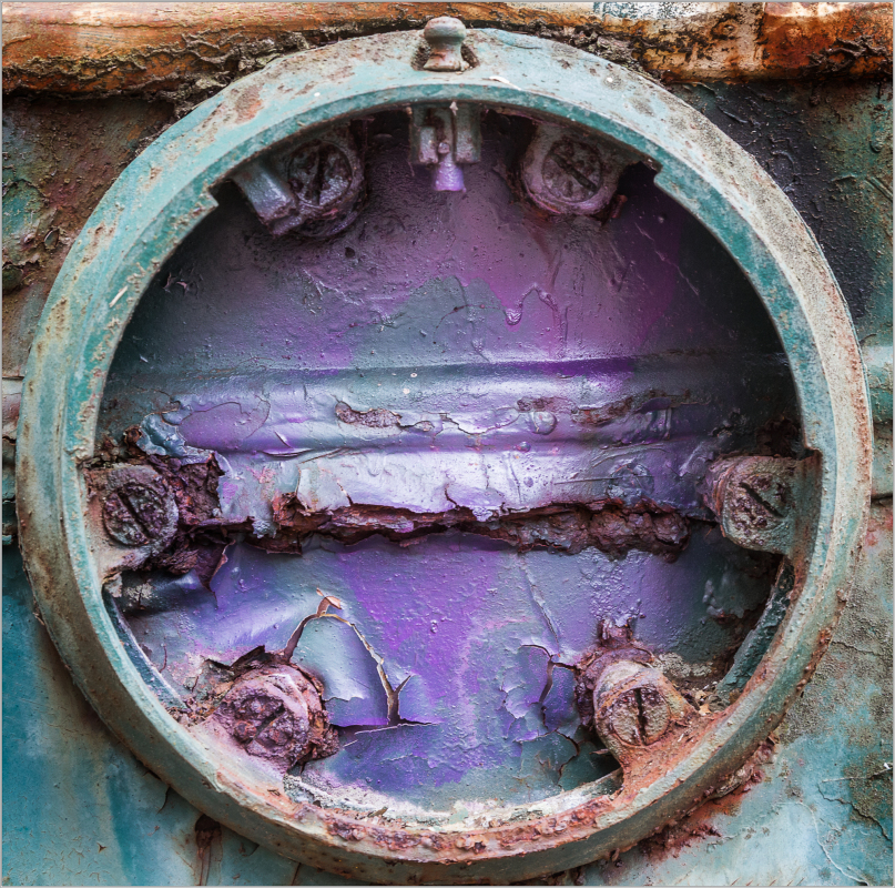 A circular, rusted opening reveals a swirl of purple hues and decay.