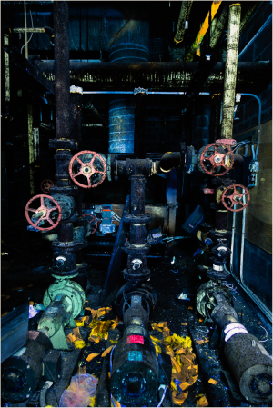 Rusty pipes and valves intertwine in a dance of shadows and light, kissed by an otherworldly glow.