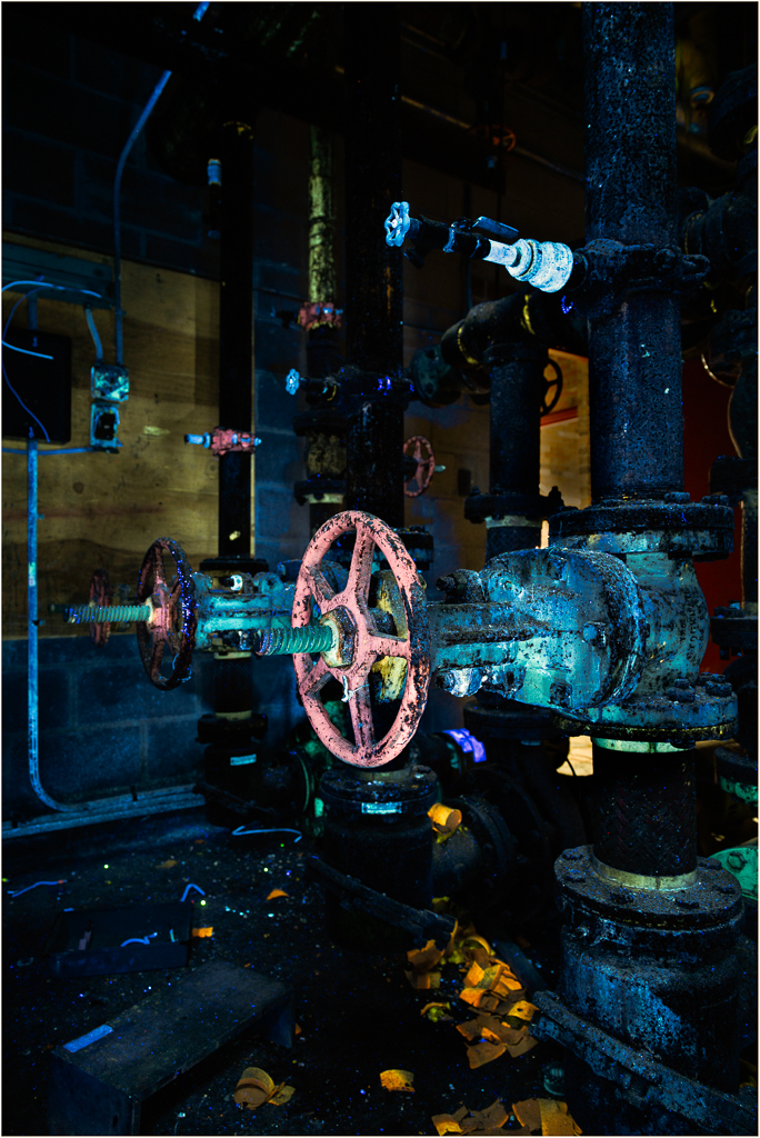 Colorful pipes and valves glowing under UV light, a quirky industrial scene.