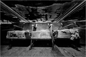 Decayed theater seats amidst shadowy desolation and ruin, whispering tales of yore.